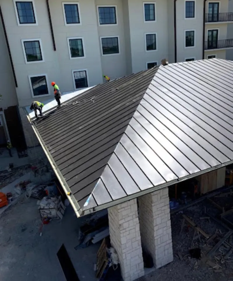 Crew installing standing seam metal roof panels on a commercial project in Tustin